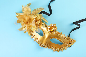 One golden carnival mask on light blue background, top view