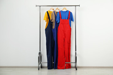 Workers' uniforms on clothing rack near grey wall indoors