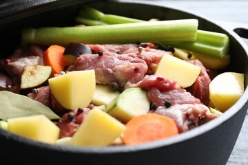 Cooking stew. Uncooked meat and vegetables in pot on table, closeup