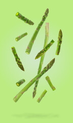 Fresh ripe asparagus falling on light green background