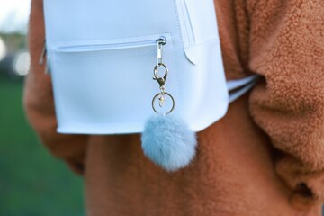 Woman with faux fur keychain on her backpack outdoors, closeup