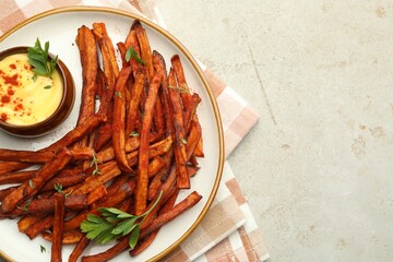 Delicious sweet potato fries with sauce on light table, top view. Space for text