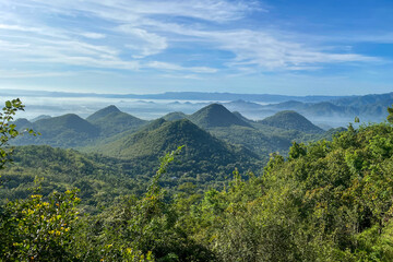 Udara segar dan A breathtaking landscape of green mountains stretches across the horizon, covered in dense forests and rolling hills. Mist gently rises from the valleys, creating a pepemandangan hijau