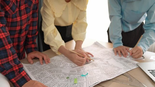 Professional engineer team discussion about house design on meeting table with architectural equipment and building blueprint scatter around at modern office. Focus on hand. Closeup. Delineation.