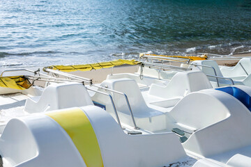 White plastic tourist catamarans stand on the seashore on the beach. Business at the resort. Close-up.