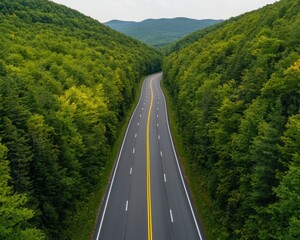Fototapeta premium Scenic road through lush green forested hills under a cloudy sky.
