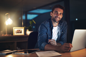 Fototapeta premium Businessman, laptop and happy for project management, networking and communication in office at night. Employee, technology and portrait for proposal, report or research with late deadline completion