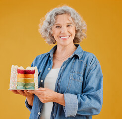Birthday, portrait and rainbow cake with old woman in studio isolated on yellow background for...