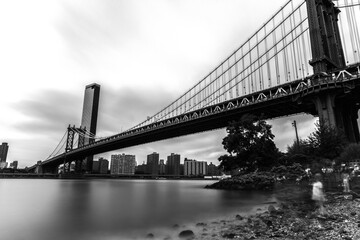 Fototapeta premium Manhattan Bridge and River in Slow Motion: A breathtaking scene capturing the elegance of the iconic bridge reflected in the shimmering waters, showcasing the dynamic beauty of New York City.