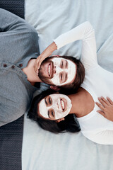 Skincare, love and face mask with portrait of couple from above for beauty, cosmetics and diy spa treatment. Wellness, collagen and detox facial with man and woman in bedroom at home for self care