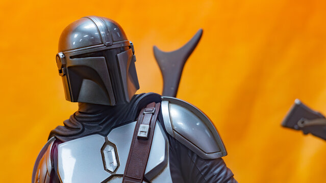 8th Comic Con Convention In GUAYAQUIL, ECUADOR - AUG 06, 2023 - Close-up of Mandalorian figurine with detailed armor against an orange background, inspired by Star Wars. Perfect for sci-fi enthusiasts