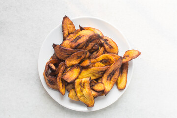 Overhead view of fried plantains on a white plate. Top view of fried ripe plantains on a plate