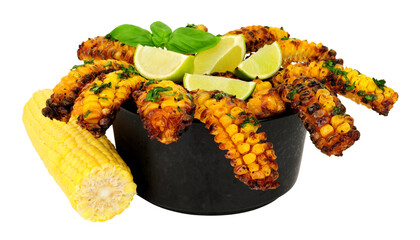 Portion of baked sweet corn ribs with herb garnish and lime wedges on a black bowl isolated on a white background