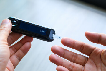 man's hands checking diabetes and hyperglycemia with digital blood sugar meter. Healthcare and medical concept	