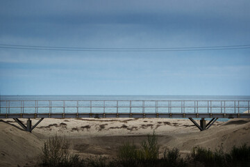 푸른 바다가 보이는 모래사장위로 만들어진 철다리.