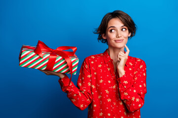 Portrait of nice young girl look giftbox empty space think wear red xmas new year shirt isolated on...