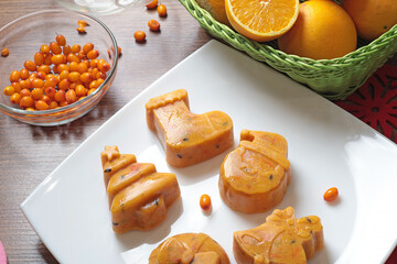 Frozen sea buckthorn and orange tea in Christmas molds on white plate in kitchen. Healthy eating and seasons. 