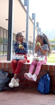 Vertical video: In school, two young biracial girls are enjoying lunch