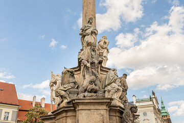 Group of sculptures at bottom part of Marian Plague Column in garden on Hradcanska Square in Prague in Czech Republic