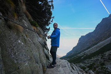 Male hiker using chain on mountain trail in high tatras, slovakia