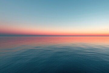 Obraz premium Calm ocean at sunset, reflecting soft hues of pink and blue across the water's surface, creating a serene atmosphere.