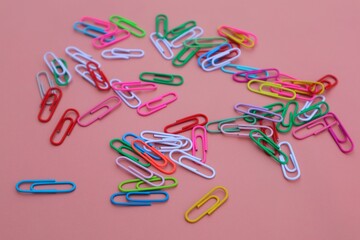 Colorful elliptical paper clips scattered on a pink background, close-up view.