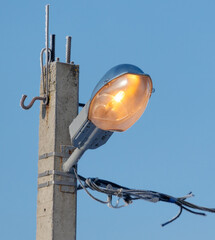 A street light is lit up and is on a pole