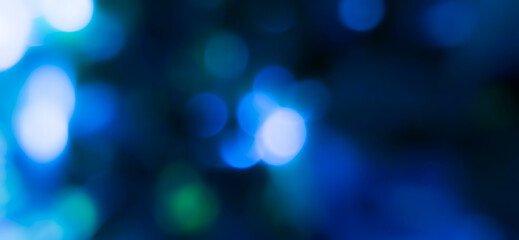 Blurred background with a cluster of blue bokeh circles and green bokeh circles scattered around. Dark bokeh photo with blurred light, Background for banner.