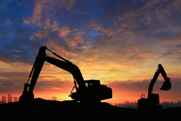 Crawler excavators silhouette are digging the soil in the construction site. on  sunset background