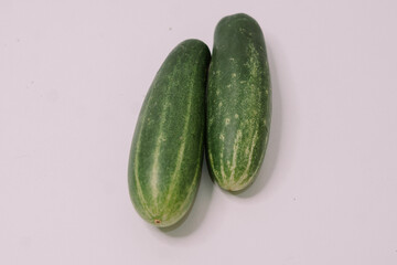 Fresh cucumbers arranged on a clean white background, highlighting their crisp texture and vibrant green color,