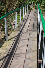 A wooden bridge with a green railing