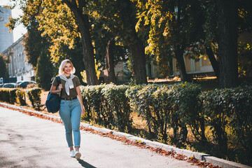 Fototapeta premium Full body photo of pretty young blonde woman wear khaki clothes tied shoulders sweater walking have fun outside urban city park