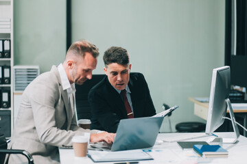 Two businessmen working together Analyze financial reports with charts and graphs while using the calculator to calculate budget, income, taxes, business growth. Startup business idea.