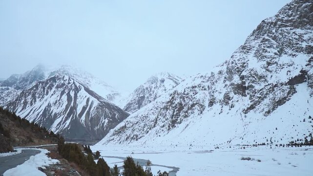 Winter mountain landscape. Road passing through snow covered mountains at Jispa, Himachal Pradesh, India. Beautiful snowy Himalayas with moody cloudy sky. Travel and holidays concept 