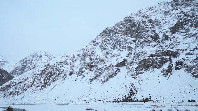 Winter landscape of snow covered mountains at Jispa in Lahaul, Himachal Pradesh, India. Snowy Himalayas in cold winter day. Moody atmosphere.
