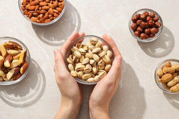 Different types of nuts in transparent glass bowls on a white background