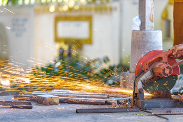 Blurred background of a craftsman using a machine, a saw blade cutting metal and sparks of scrap metal coming out. Use of tools and technology in construction.
