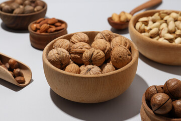 Various nuts in wooden bowls on a gray background