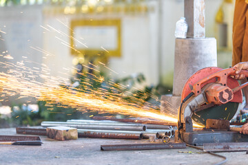 Blurred background of a craftsman using a machine, a saw blade cutting metal and sparks of scrap metal coming out. Use of tools and technology in construction.