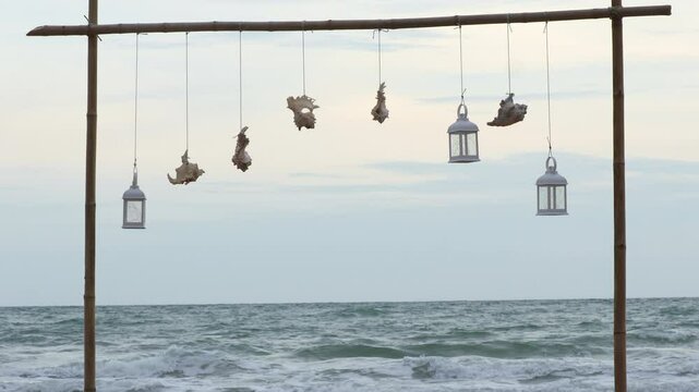 Natural seashell and lantern hanging on bamboo railing with blurred sea background. Concept enjoy the relaxing nature.