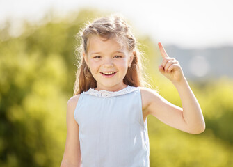 Happy, pointing and portrait of child in park with smile for playing, childhood and adventure outdoors. Nature, mockup and young girl with hand gesture for direction, signal and excited in playground