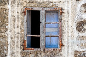 Picturesque rustic old window with wooden frames and blue shutters in a stone house