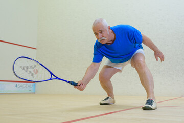 an elderly man playing squash
