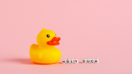 Yellow rubber duck and word cubes on pink background. Swear words humor concept.