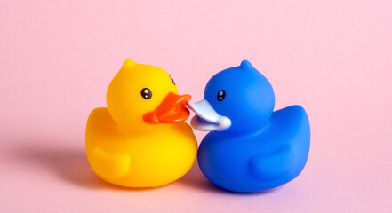 Yellow and blue ducks kiss on pink background.