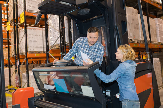 woman talking to man working with a forklift