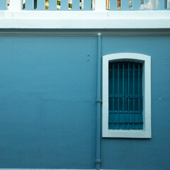 Blue iron and wooden color window with blue color concrete wall on the side of tree shadow, white town building concrete walls for photo shoot