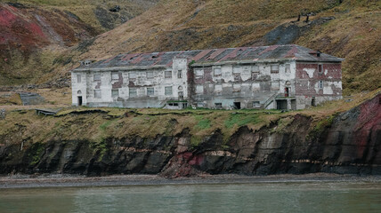 Abandoned building on the Grumant shoreline, featuring eroded cliffs and rich history