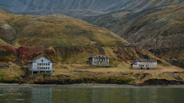 Abandoned buildings along the shoreline in Grumant, Svalbard surrounded by rugged landscapes