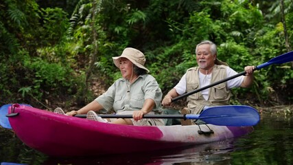 Happy Asian family senior couple kayaking in the river on summer holiday vacation. Healthy elderly people enjoy and fun outdoor active lifestyle travel nature, sport and rowing a boat in the lake.
